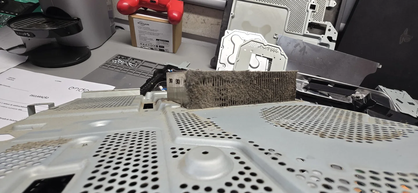 Consola PS4: Acumulação de pó no dissipador, fotografada antes da limpeza.